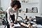 A lady in an apartment leaning over a desk and writing something on a piece of paper on a clipboard
