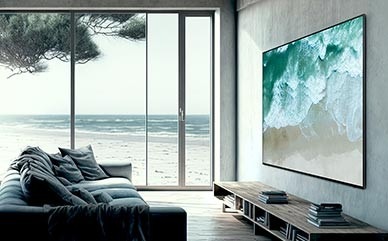 A 98 inch Supersize TV is mounted on a wall in a living room displaying the ocean.