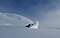 Snowboarder na snje\u017Enoj planini snimljen odozdo naspram \u010Distog plavog neba, stvaraju\u0107i val snje\u017Enog praha.