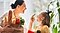 Mother and her daughter looking at each other with big smiles, holding grocery shopping bag filled with vegetables.