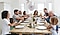 A smiling family sits around a dining room table getting ready to pull Christmas crackers