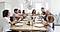 A smiling family sits around a dining room table getting ready to pull Christmas crackers