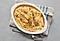 Parsnip strips covered in parmesan sauce with a toasted cheese and other ingredients are in a white bowl.