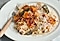 Creamy risotto made with roasted butternut squash, woody spices, parmesan and a splash of white wine is on an white plate.