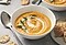 A bowl of vegetable soup with dill on it is on a table.