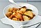 Golden roasted potatoes seasoned with lemon zest, sea salt and bayleaves are in a white bowl.