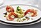 Three pan-seared prawns and a cucumber salad are presented on a white plate.