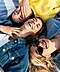 Three women laying down together and wearing earbuds.