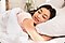 A woman smiling with her head on a pillow in bed.
