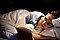 A woman lays on her side in bed while reading a book.