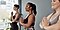Three women in a yoga studio wearing workout clothes and standing with their hands in prayer position.