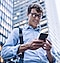 A man with blue shirts smiling when watching smartphone