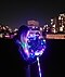 Summer night photography of a woman holding a glowing LED balloon while bokeh lights glow in the background