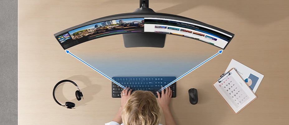 A bird's-eye view of a woman looking at the curved monitor screen. Two arrows pointing at the edges of the screen.