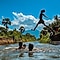 Group of young men swimming in the lake and one man jumping into the water, spreading his arms and legs in the air