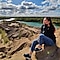 A woman sitting on rock mountain smiling with her eyes closed