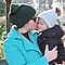 Mother kissing her baby boy in the cheek and boy smiling