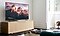 Inside a brightly lit living room, The Frame TV is placed on a TV cabinet using the studio stand option and is seen from a medium side closeup and. An image of a mountain range can be seen on the screen.
