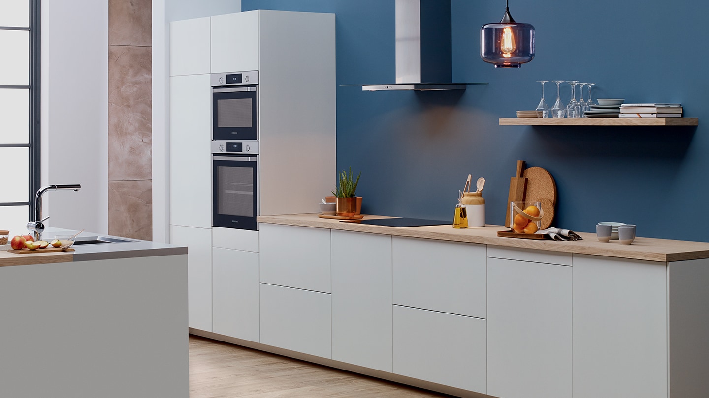 Un intero set di elettrodomestici da incasso Samsung come frigoriferi, forni e forni compatti installati in una cucina bianca premium.