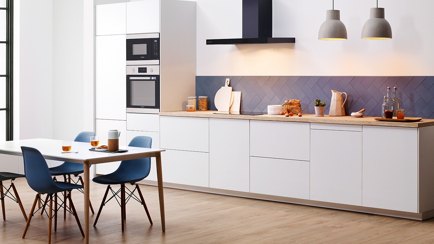 Un intero set di elettrodomestici da incasso Samsung come frigoriferi, forni, forni compatti, piani cottura lavastoviglie e cappe installati in una cucina bianca premium.