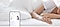 Una persona dorme serenamente nel suo letto indossando un anello intelligente al dito. Sullo schermo dello smartphone viene mostrata la funzionalità “Punteggio del sonno” con 80 punti e la valutazione “Buono”.