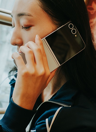 女性が、折りたたみスマホ「Galaxy Z Flip6(ギャラクシーZフリップ6)」を耳に当てて通話している。