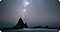 A beach rock formation in front of a starry night sky.