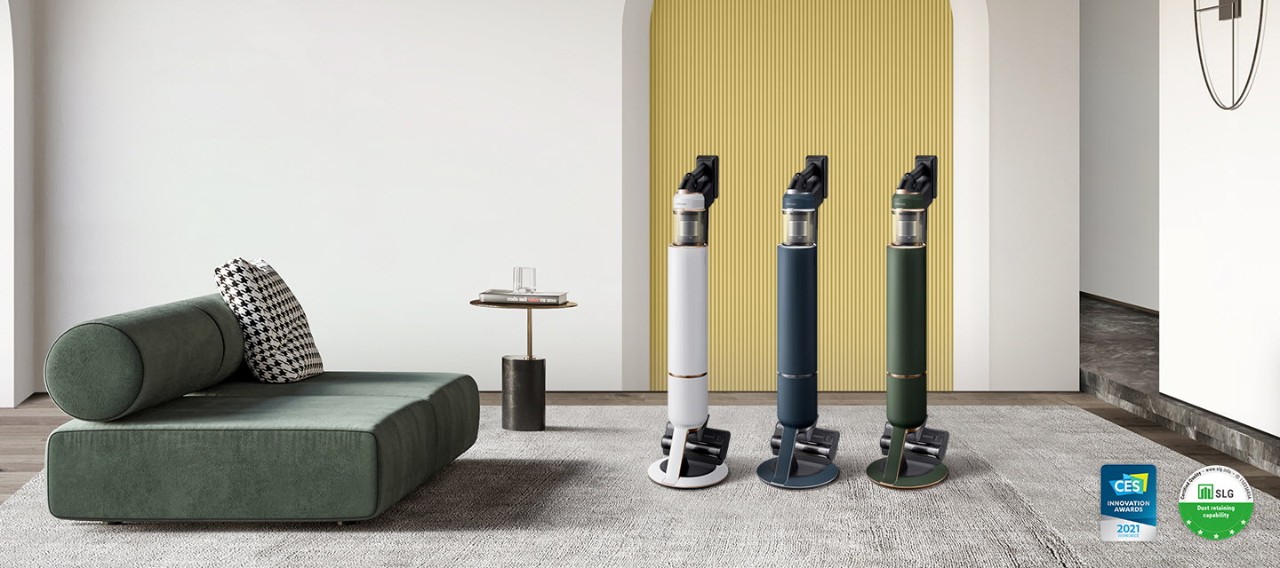 3 Bespoke JET models in Misty White, Midnight Blue, and Woody Green are standing in a modern room in front of a white wall with a yellow door. On the bottom right, there is a CES 2021 Innovation Awards logo for the All-in-one Clean Station and another logo for the SLG 5-star Certification for dust retaining capability.