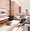 Una familia en el sofá de la sala de estar que mira las fotos familiares en el televisor de la pared con el modo Ambiente de Samsung para rememorar sus recuerdos familiares.