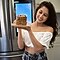 A woman stands in front of her fridge holding up a plate of pancakes.