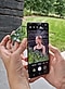 Hands holding a small mirror and a black Galaxy S21 Ultra 5G with the screen showing a girl looking to her left