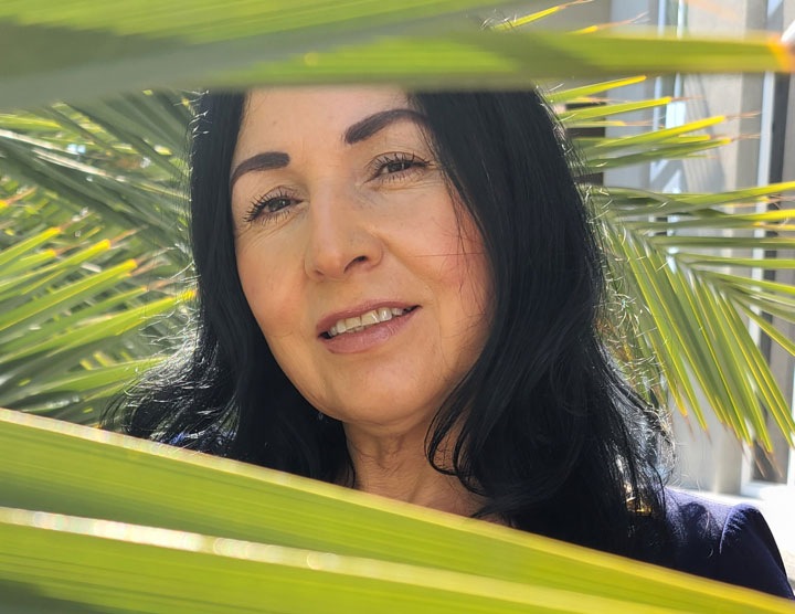 Portrait of Bryant's mom on a sunny day in front of palm trees.