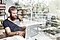A double-exposure shot of a man sitting at a desk on his laptop, there is a book shelf in the background