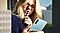 A lady holding an S Pen to her lips while looking at her Galaxy Note10 phone