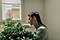A lady crouched down and watering a plant