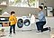 A boy and his father are laughing about the son’s crayon-stained shirt. The father is kneeling in front of the QuickDrive™, holding out a fresh and clean white t-shirt that just came out of the wash for the boy to change into.