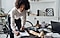 A lady in an apartment leaning over a desk and writing something on a piece of paper on a clipboard