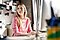 A lady wearing a pink top sitting at a desk and looking off into the distance