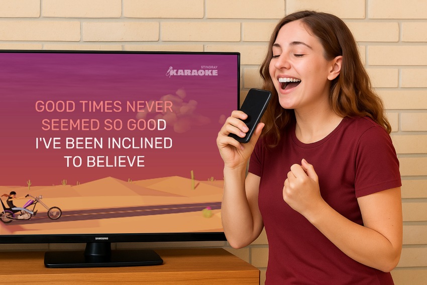 A girl is singing in front of a TV using her phone as a microphone. The TV screen has Karaoke lyrics displyed.
