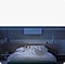 A person sleeps peacefully in a dark room, lying under a Samsung wall-mounted air conditioner.