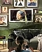 A woman watches The Frame as it displays the Girl with a Pearl Earring painting, which is surrounded by other art pieces.