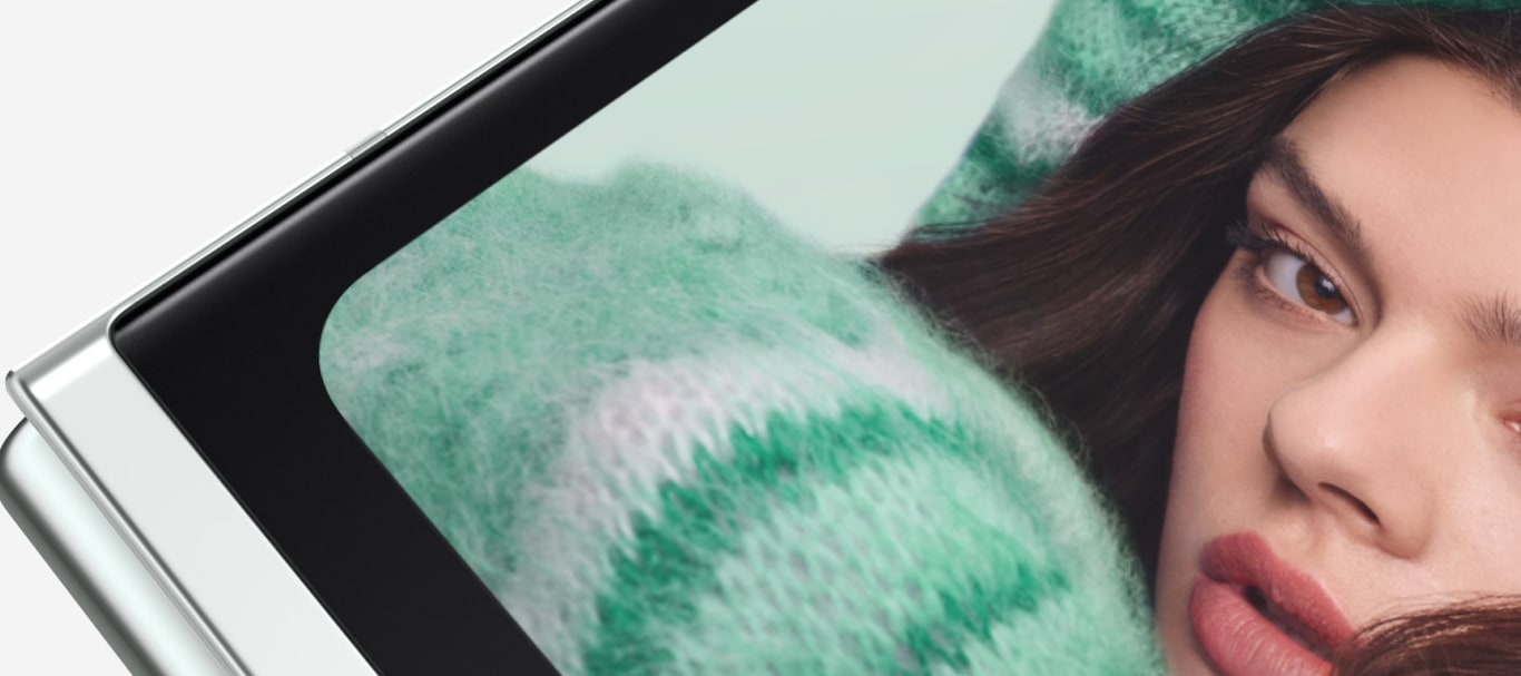 Un Galaxy Z Flip5 plegado gira en la esquina de la bisagra y se detiene con la Cover Screen hacia adelante y la bisagra apunta hacia abajo. La Cover Screen muestra una selfie FlexCam. El Galaxy Z Flip5 se mueve hacia un lado 
