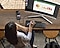 A birds-eye view of a lady sitting at a desk and using Samsung’s DeX Station to make working remotely a breeze