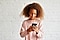 A young girl in a pink sweater holds a black Galaxy phone in portrait mode with both hands. She smiles as she looks at the screen as if she's watching a show.