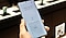 Primer plano de las manos de un técnico que repara teléfono sobre una mesa. El teléfono ha sido desmontado con los componentes interiores expuestos.