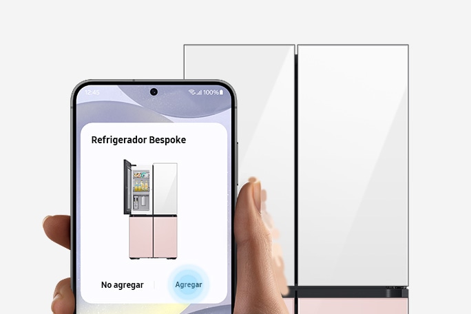 Frente a un refrigerador, una mano sostiene un smartphone Galaxy que muestra la aplicación SmartThings con una tarjeta que sugiere vincularla con el refrigerador. La interfaz del usuario de la aplicación también se ve dentro del refrigerador.