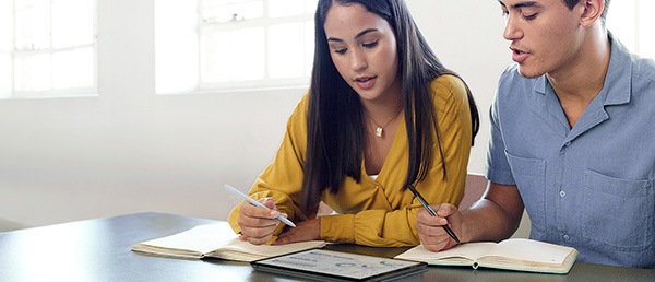 A woman and man sitting side by side, using a Galaxy Tab and S Pen to study together.
