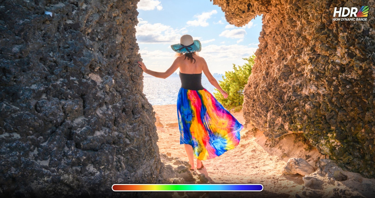Comparison of Standard Dynamic Range (SDR) and High Dynamic Range (HDR) on a Samsung ViewFinity monitor. A woman is standing between two rocky cliffs with vibrant colors and enhanced details on the HDR side. A slider in the center contrasts the differences in brightness and color depth between 8-bit SDR and 10-bit HDR.