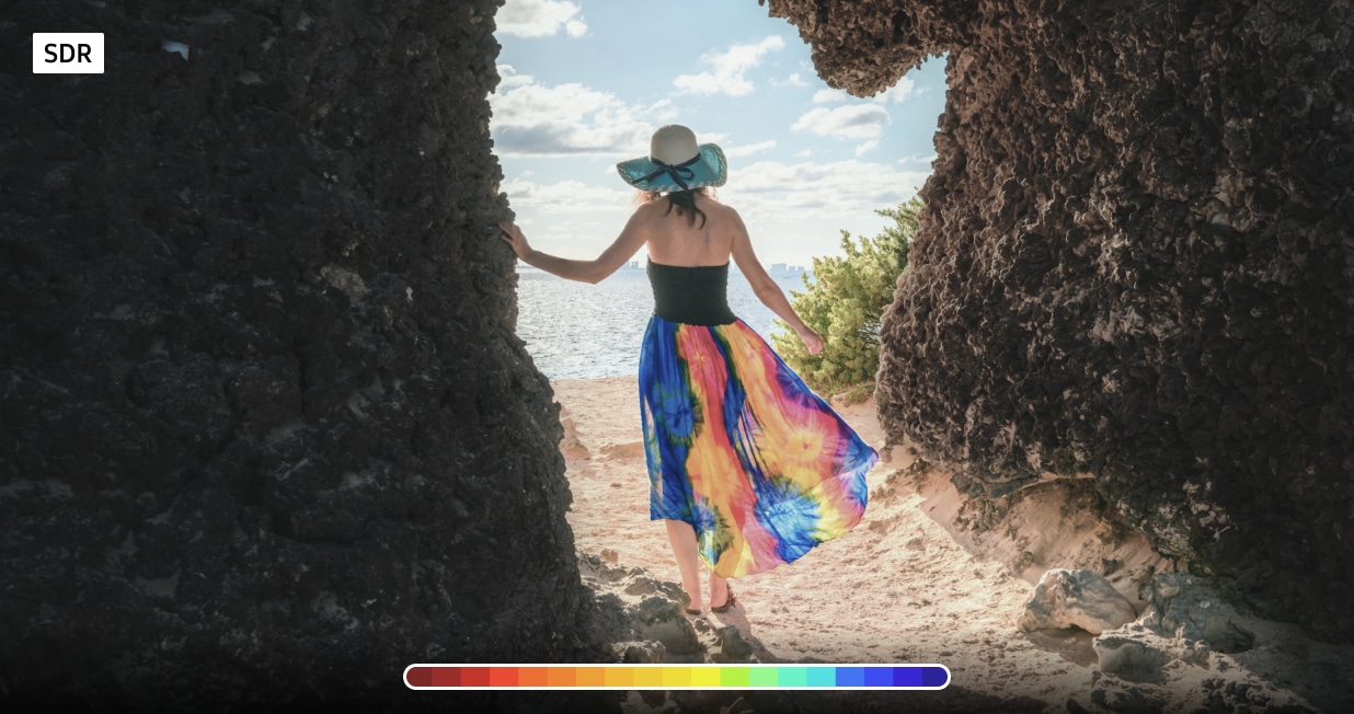 Comparison of Standard Dynamic Range (SDR) and High Dynamic Range (HDR) on a Samsung ViewFinity monitor. A woman is standing between two rocky cliffs with vibrant colors and enhanced details on the HDR side. A slider in the center contrasts the differences in brightness and color depth between 8-bit SDR and 10-bit HDR.