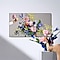 Een Neo QLED 8K TV toont een levendig boeket terwijl twee handen bijpassende echte bloemen rangschikken.